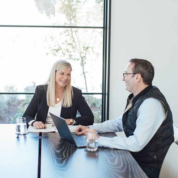 strategic sale - a woman standing at a whiteboard in an office talking to a man who is sitting in front of her